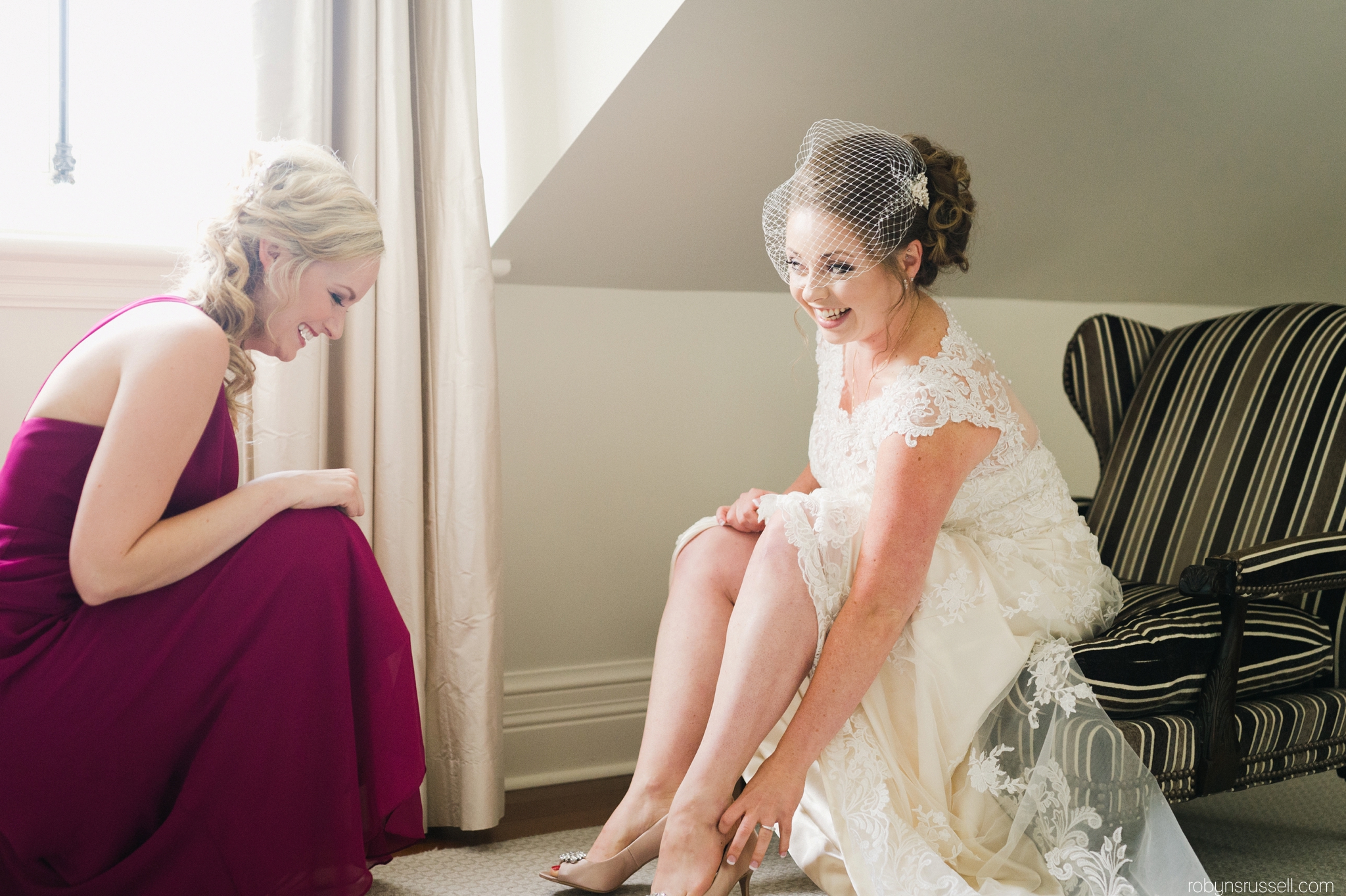 17-bride-getting-shoes-on-with-bridesmaid.jpg